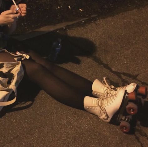 a woman is sitting on the ground with her skateboard next to her legs and shoes