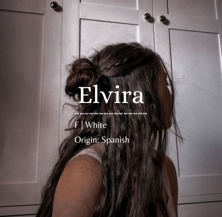 the back of a woman's head with long hair in front of white cabinets