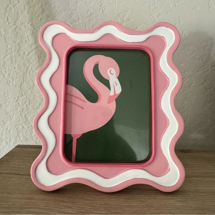 a pink and white flamingo frame sitting on top of a wooden table