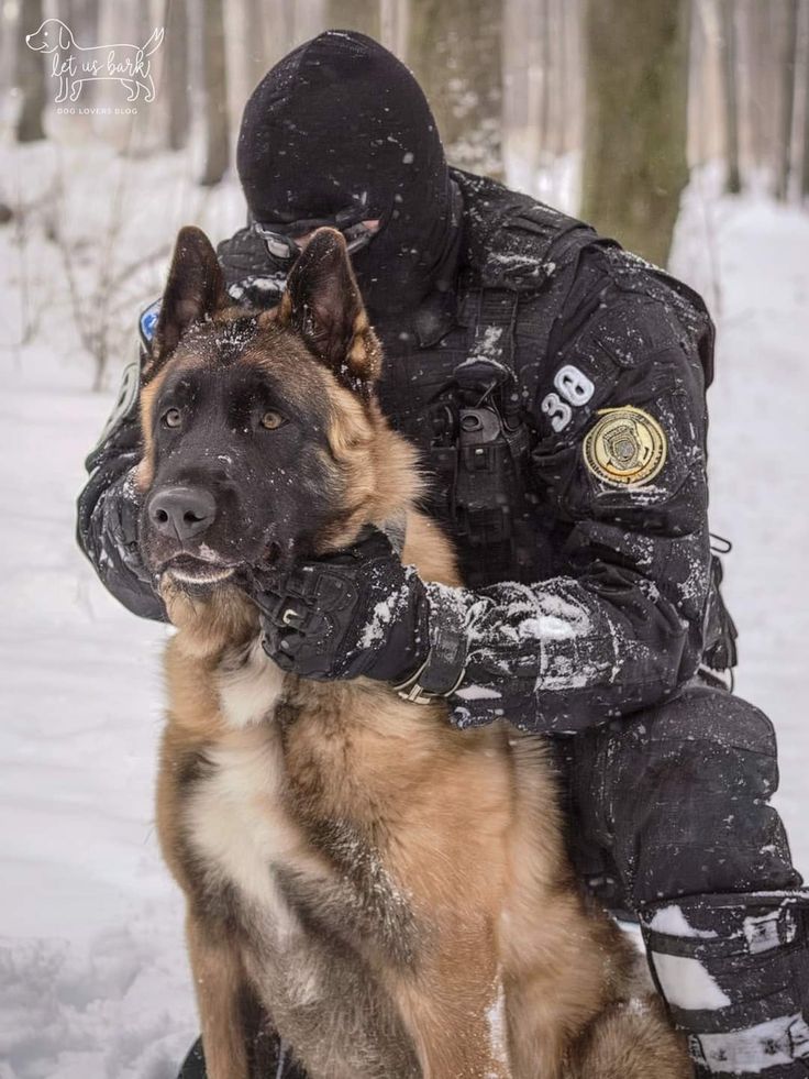 a police dog sitting on the back of a man in snow gear with his arm around him