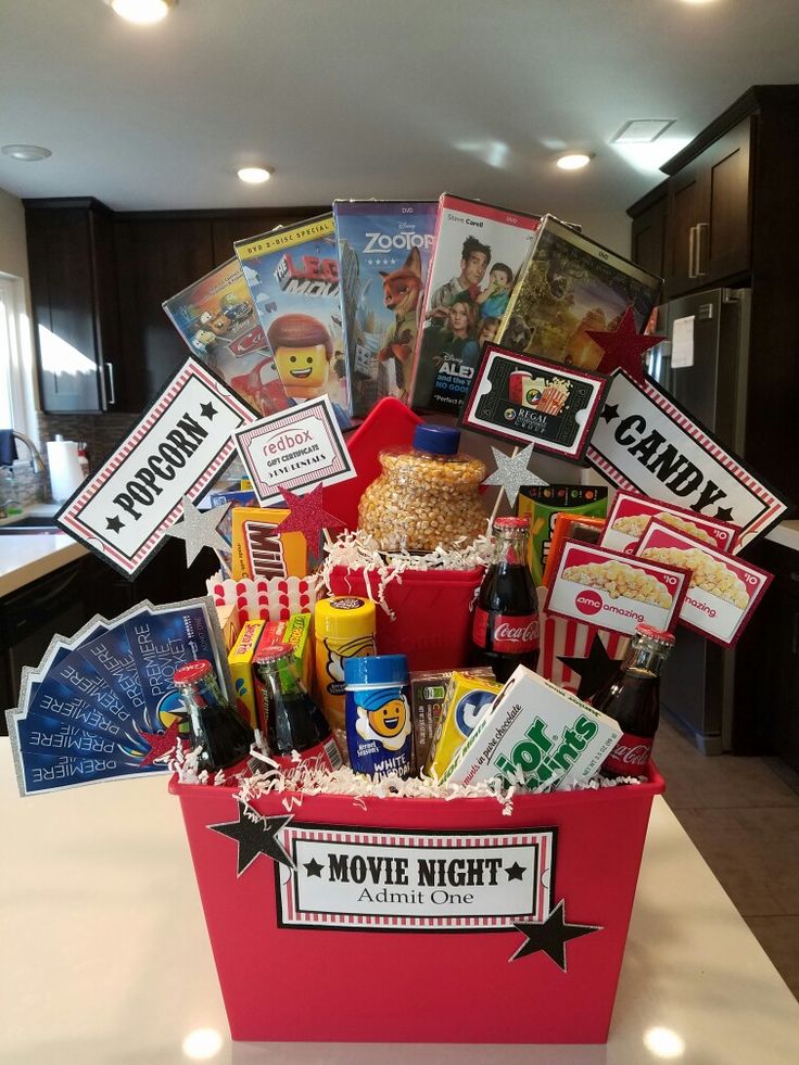 a movie night gift basket with popcorn, movies and drinks on the counter in a kitchen