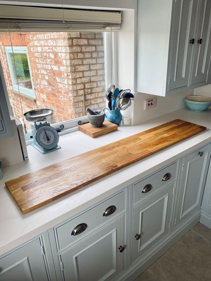 a kitchen counter with a wooden cutting board on top of it next to a window