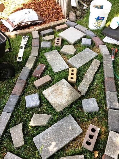 some bricks laying on the ground in front of a garden hose and other items that have been placed around them