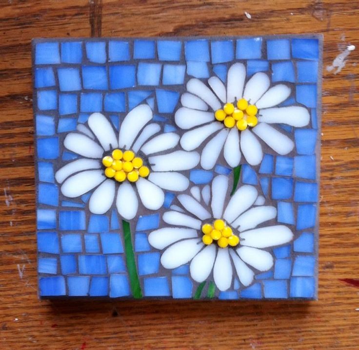 a blue and white tile with flowers painted on the side, sitting on a wooden table