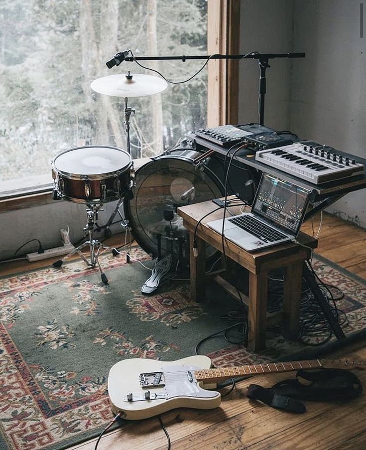 a recording studio with guitars, drums and other musical equipment in front of a window