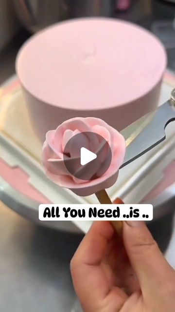 a person holding a pink flower in front of a cake with the words, all you need is