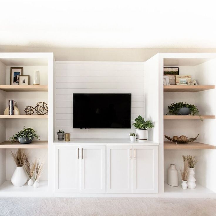 a living room filled with furniture and a flat screen tv on top of a wooden shelf