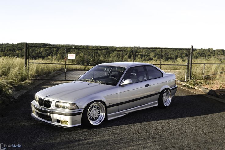 the silver car is parked on the side of the road in front of a fence