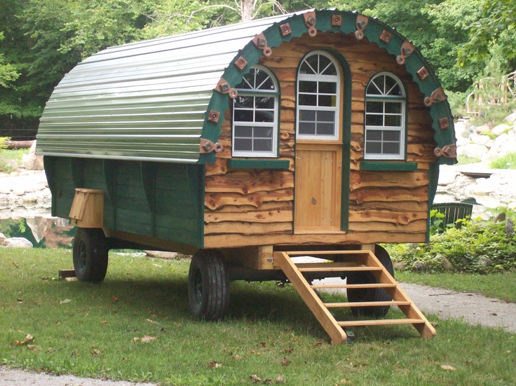 a green and white tiny house sitting in the grass