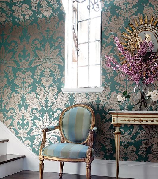 a blue chair sitting in front of a window next to a stair case with flowers on it