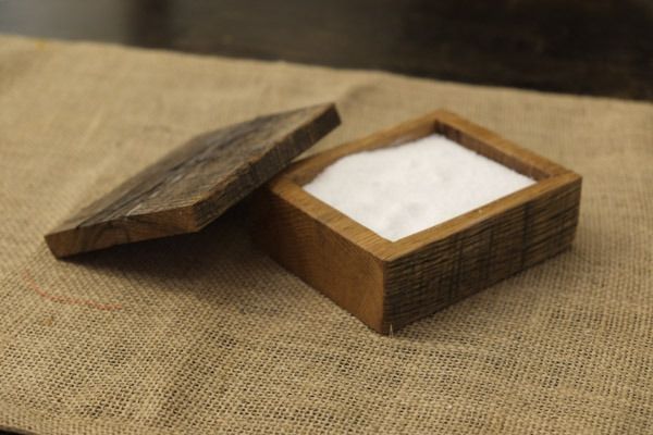 a small wooden box sitting on top of a burlied tablecloth covered in white powder