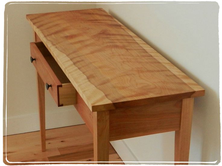 a wooden table with two drawers on it's sides and a white wall in the background