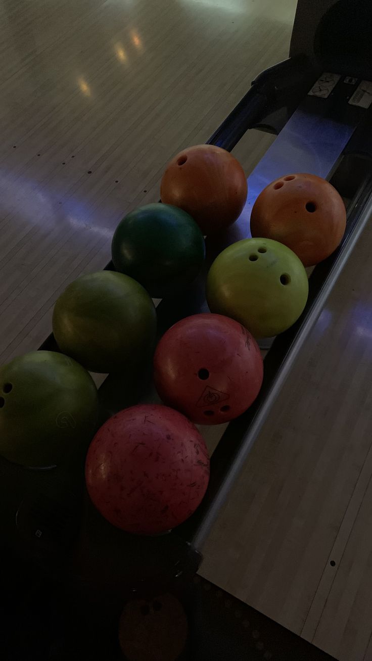 several bowling balls are lined up in a row at the end of a bowling alley