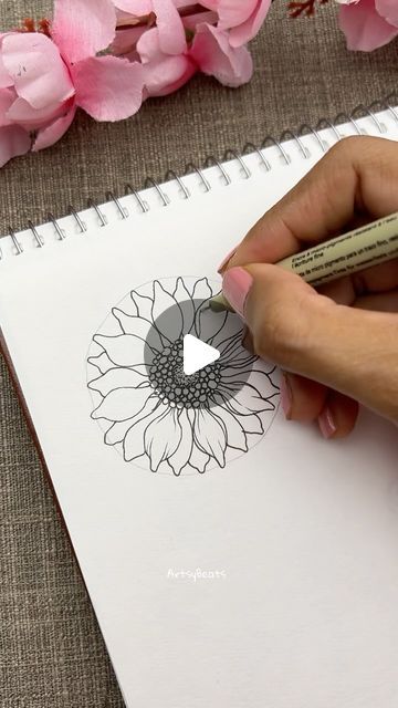 someone is drawing a flower on a piece of paper