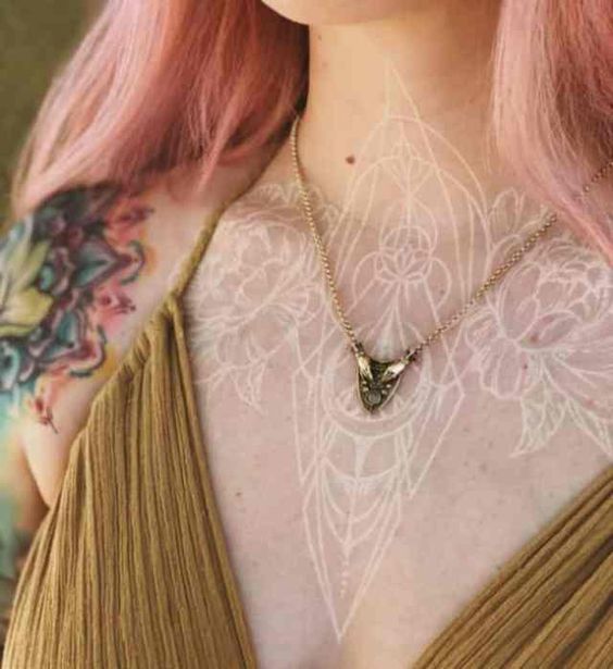 a woman with pink hair and tattoos on her chest