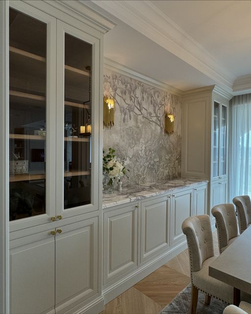 a dining room table and chairs in front of a wall with built - in cabinets