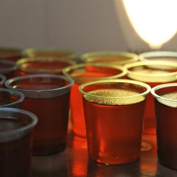 there are many cups with drinks in them sitting on the table next to each other