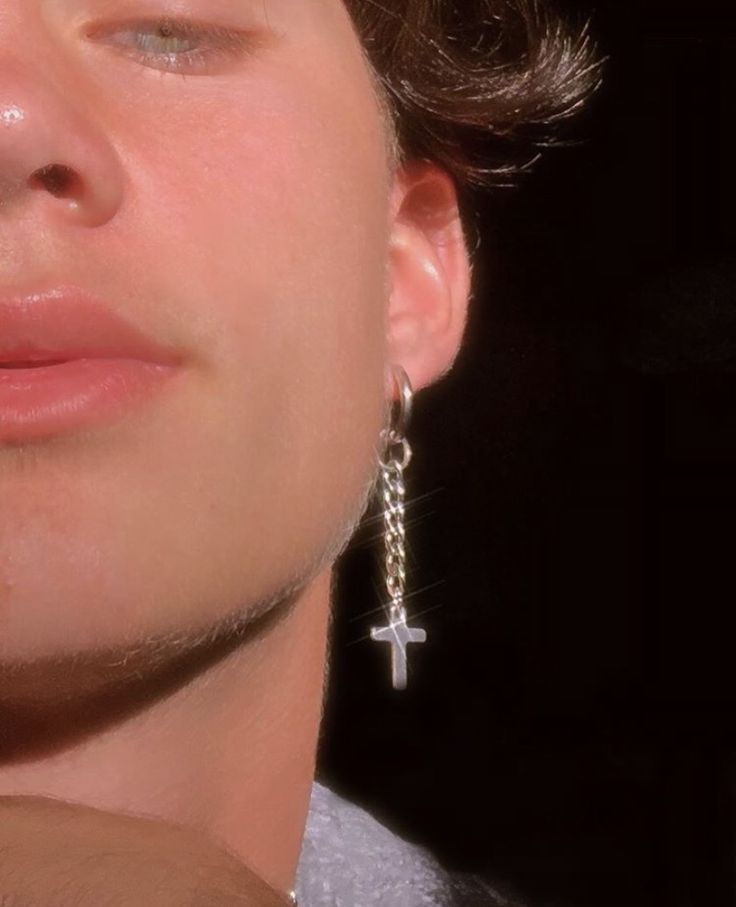 a close up of a person wearing earrings with a cross hanging from it's ear