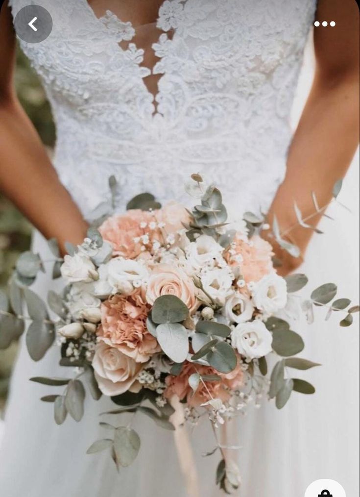 a bride holding a bouquet of flowers and greenery