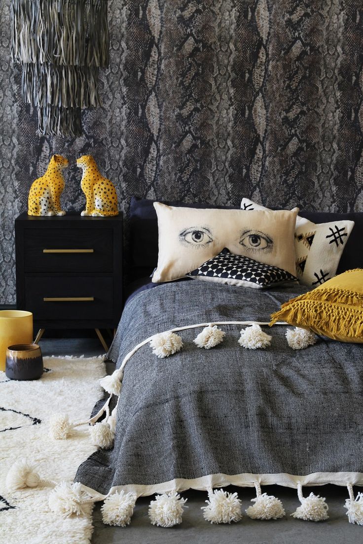 a black and white bedroom with decorative wallpaper on the walls, bedding and pillows