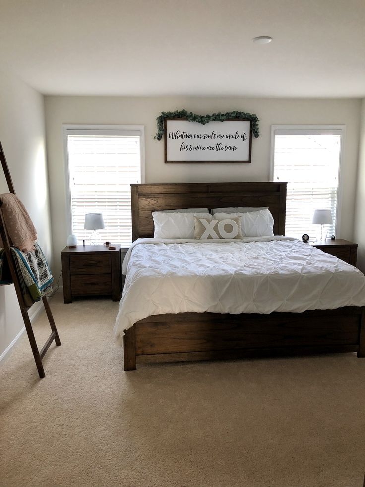 a bedroom with a bed, ladder and two windows