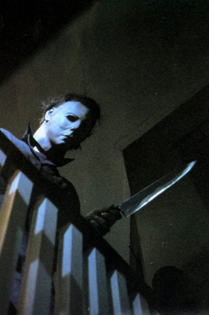 a man holding a knife in his hand while standing next to a stair railing at night