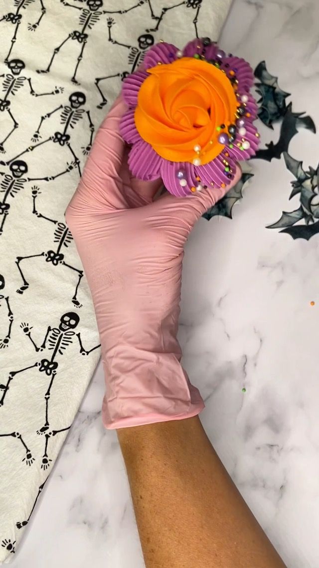 a person in pink gloves holding a flower on top of a white and black table cloth