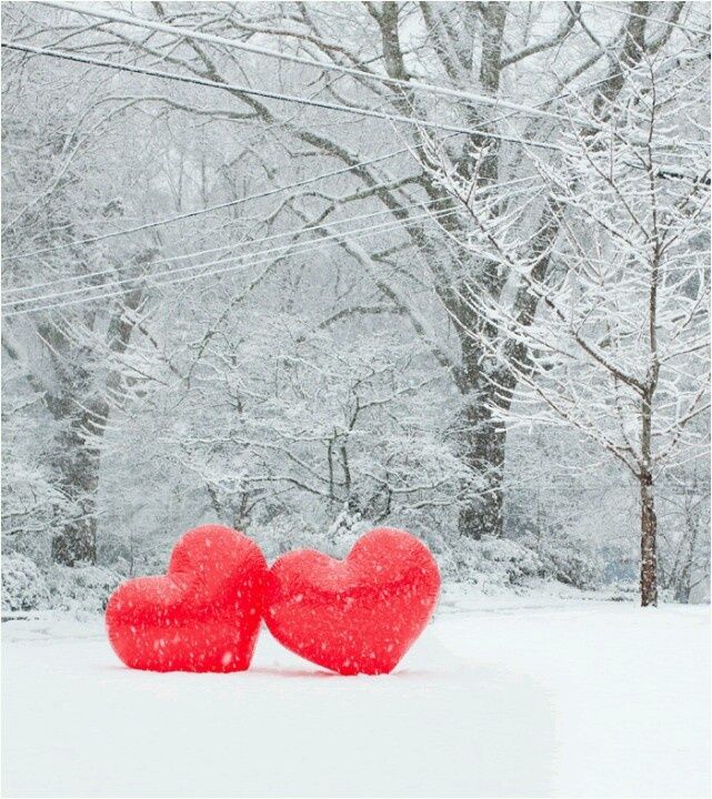 two red hearts sitting in the snow