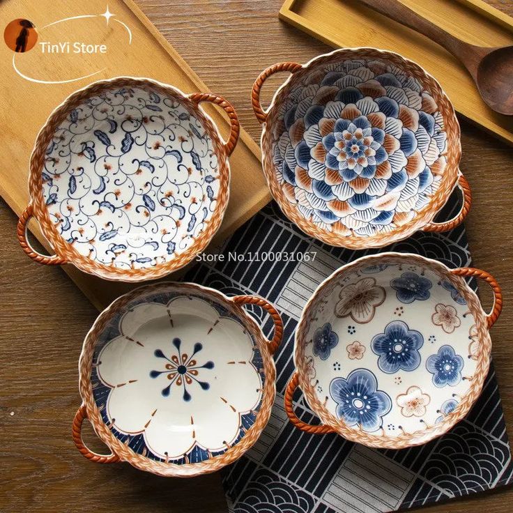 four blue and white dishes sitting on top of a wooden table next to utensils