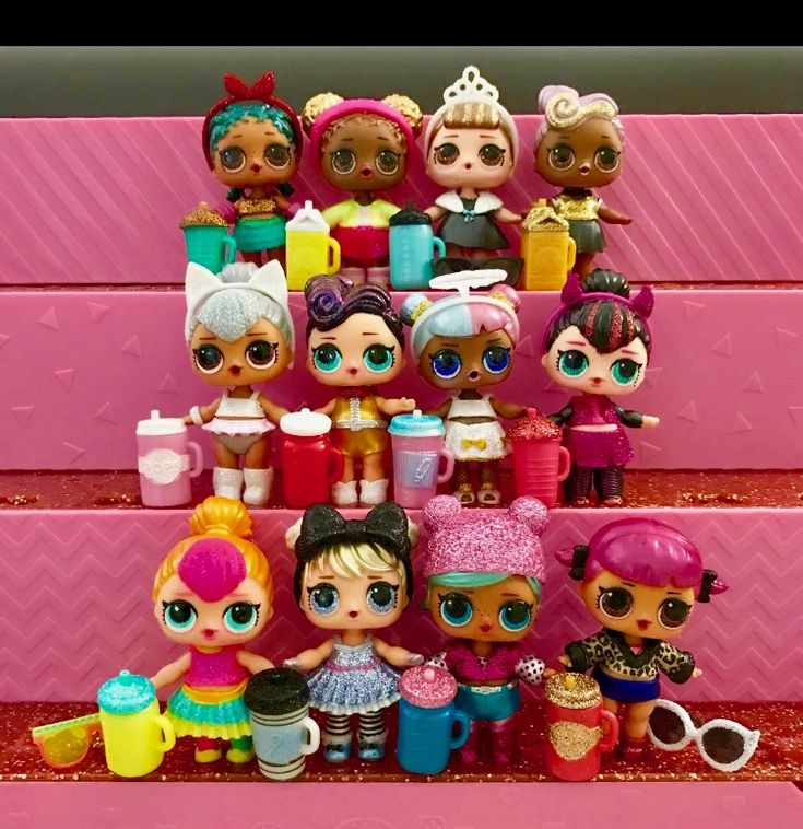 there are many little dolls sitting on the shelf together in front of some pink wall