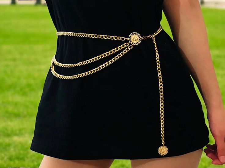 a woman wearing a black dress and gold chain belt