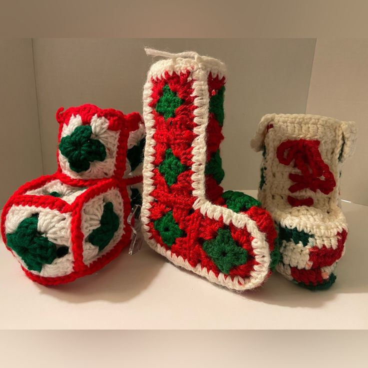 three crocheted christmas boots and one boot with holly leaves on the side, all in red and white