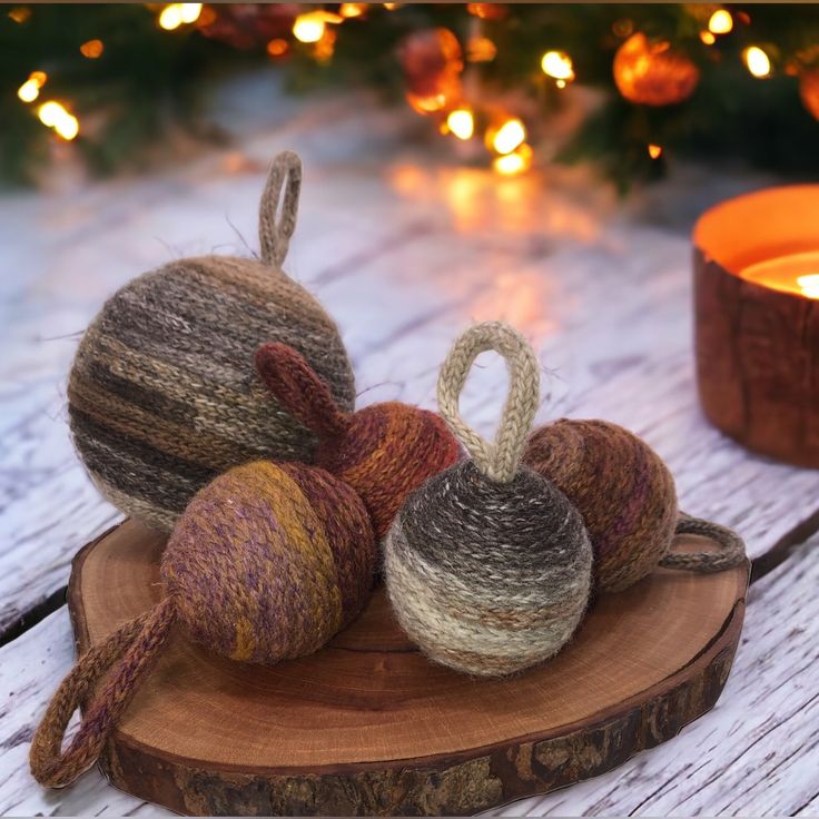 three balls of yarn sitting on top of a piece of wood next to a lit candle