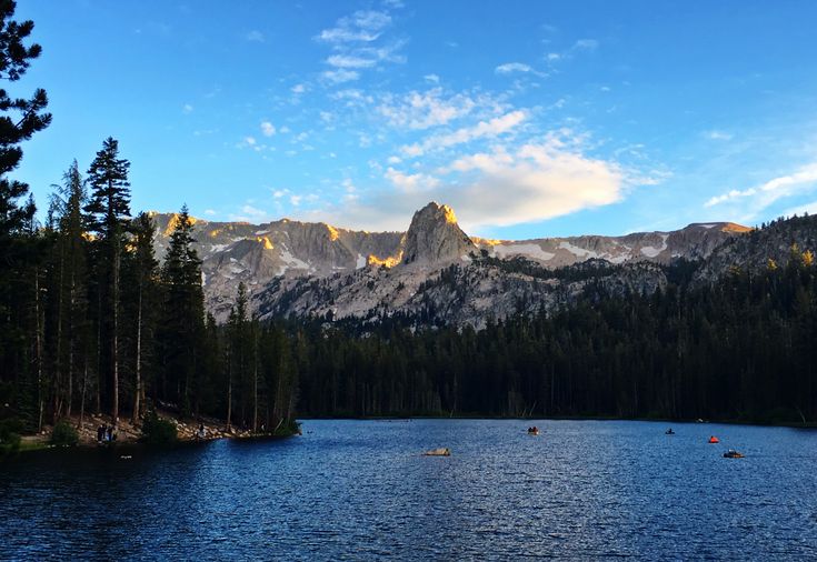 a lake surrounded by trees with mountains in the background