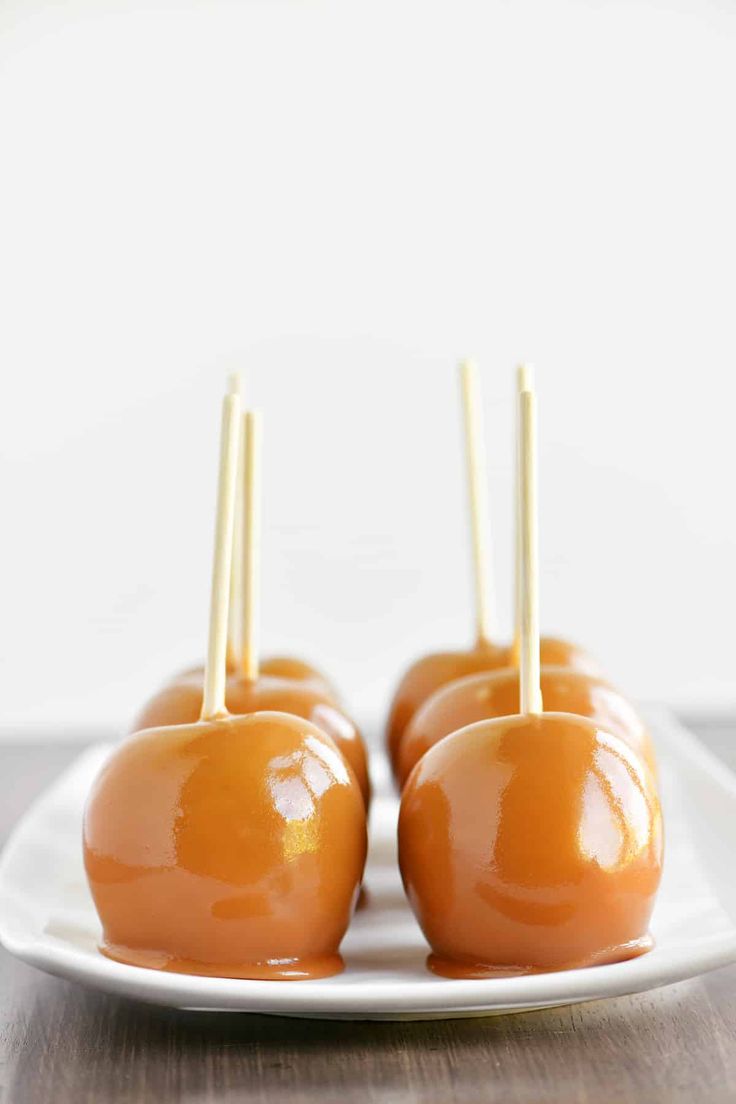 caramel apples on a plate with toothpicks sticking out of the top one