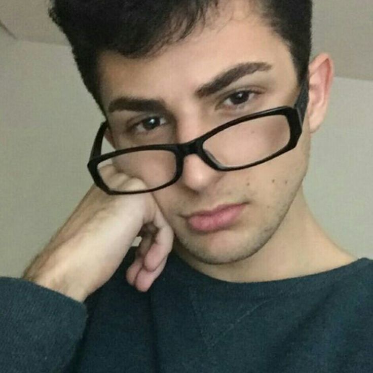 a young man wearing glasses looking at the camera