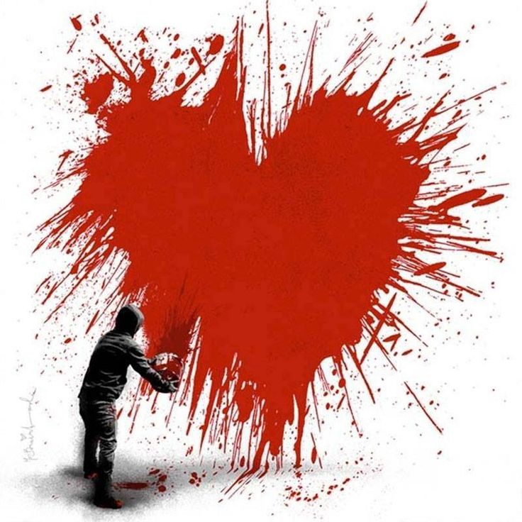 a man holding a red heart with paint splatters on it