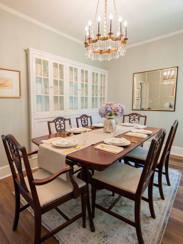 a dinning room table with chairs and plates on it in front of a chandelier