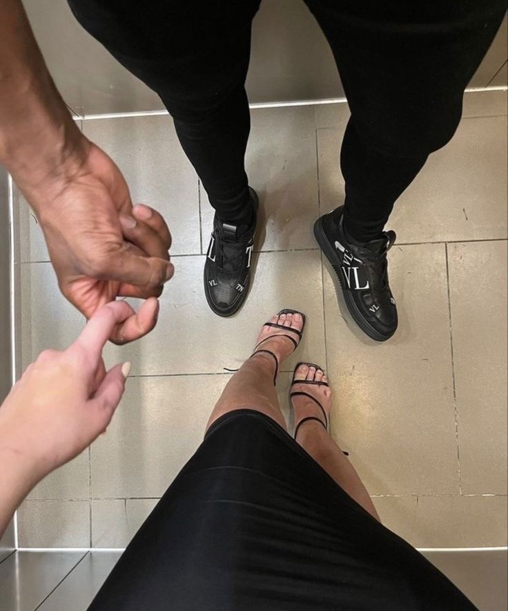 two people holding hands while standing on the floor