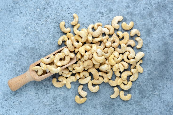 some cashews on a blue surface with a wooden spoon in the middle,