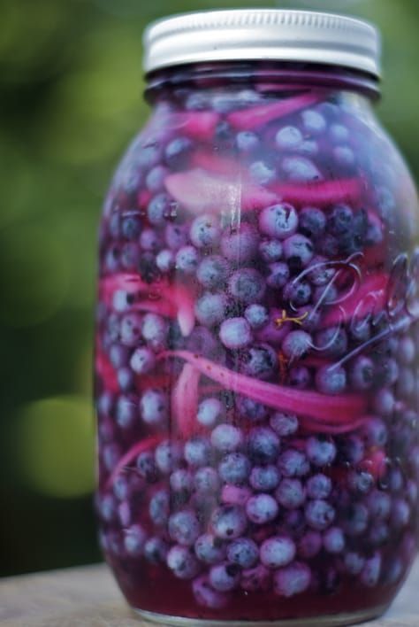 a jar filled with blueberries sitting on top of a wooden table