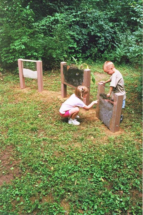 two children are playing in the grass near some wooden boxes with plants growing out of them