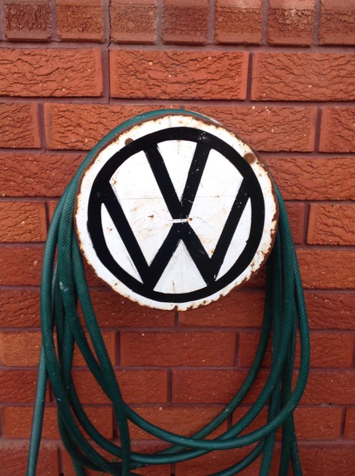 a white and black sign mounted to the side of a brick wall next to a green hose