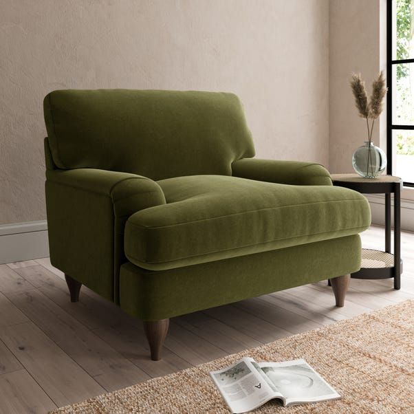 a green couch sitting on top of a hard wood floor next to a glass vase