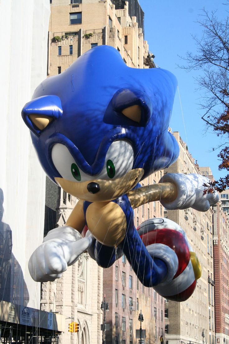 an inflatable balloon shaped like sonic the hedgehog floats down a city street