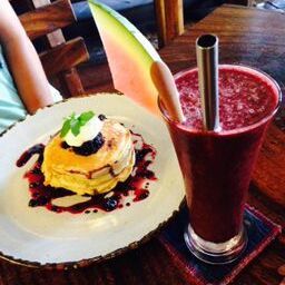 a person sitting at a table in front of a plate with food on it next to a drink