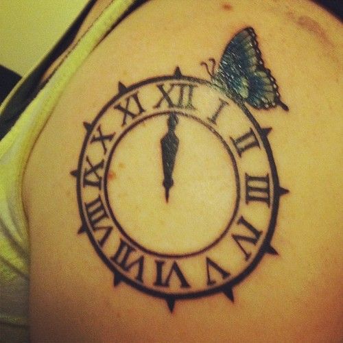 a woman with a butterfly on her shoulder has a clock tattoo on her left arm