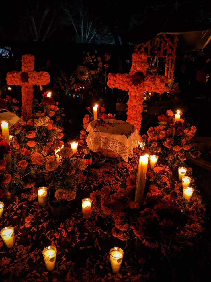 candles are lit in the middle of a garden with crosses and flowers on it at night