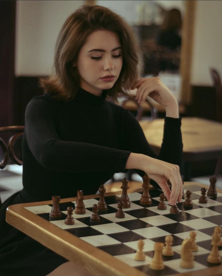 a woman sitting at a table playing chess