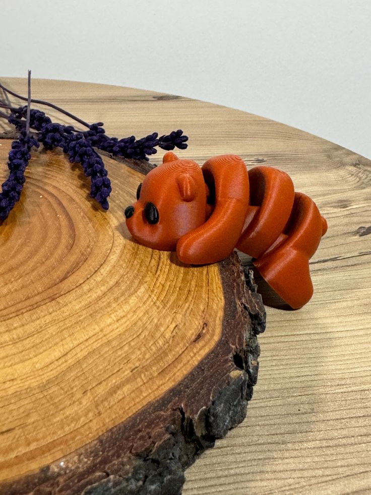 an orange toy bear laying on top of a piece of wood